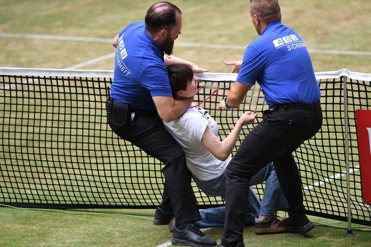 A woman who invaded the court is held by security during the men's singles final match at the ATP 500 Halle Open tennis tournament in Halle, western Germany, on June 19, 2022.,Image: 701055086, License: Rights-managed, Restrictions: , Model Release: no, Credit line: Profimedia