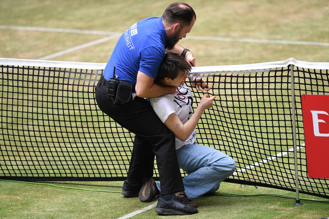 A woman who invaded the court is held by security during the men's singles final match at the ATP 500 Halle Open tennis tournament in Halle, western Germany, on June 19, 2022.,Image: 701055088, License: Rights-managed, Restrictions: , Model Release: no, Credit line: Profimedia