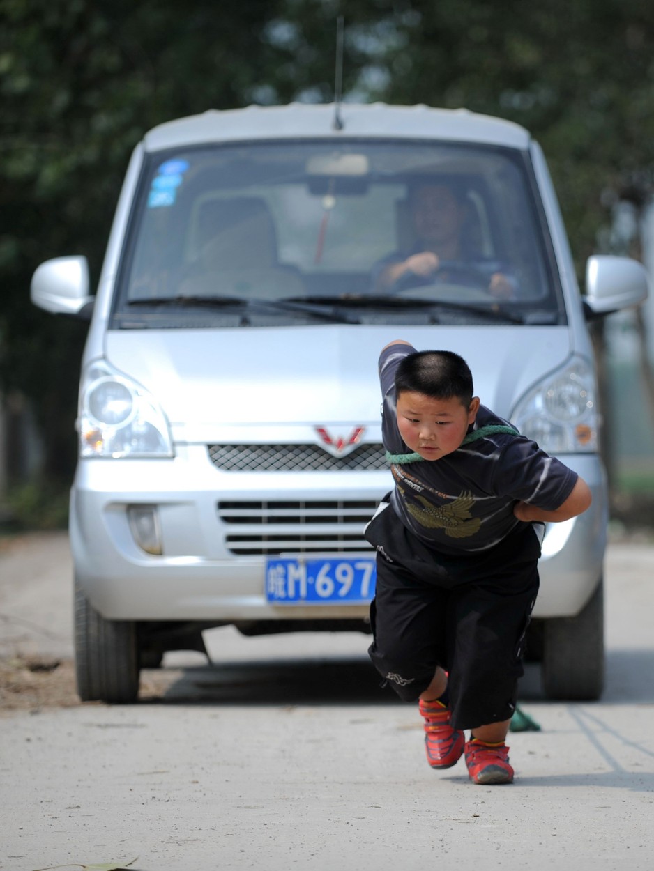 7-year-old Yang Jinlong pulling a car
Super strong 7-year-old able to pull a car, Chuzhou, Anhui Province, China - 23 Sep 2012
A 7-year-old Chinese boy is so strong that he is able to pull a car. Recently Yang Jinlong demonstrated his strength with a series of tests in his village in Chuzhou, eastern China's Anhui Province. Yang at first carried his mother, who weighs 70kg, before picking up his 90kg father and running round the yard several times. He then picked up a 40kg bag of grain  and jogged around with it on his shoulder for ten minutes. Following the urging of locals, Yang then tried pulling a van weighing 1.18tons. Bending his body forward and pulling the van with a thick rope, Yang walked faster and faster with the van, and later even ran with it. According to Yang's mother her son has a 