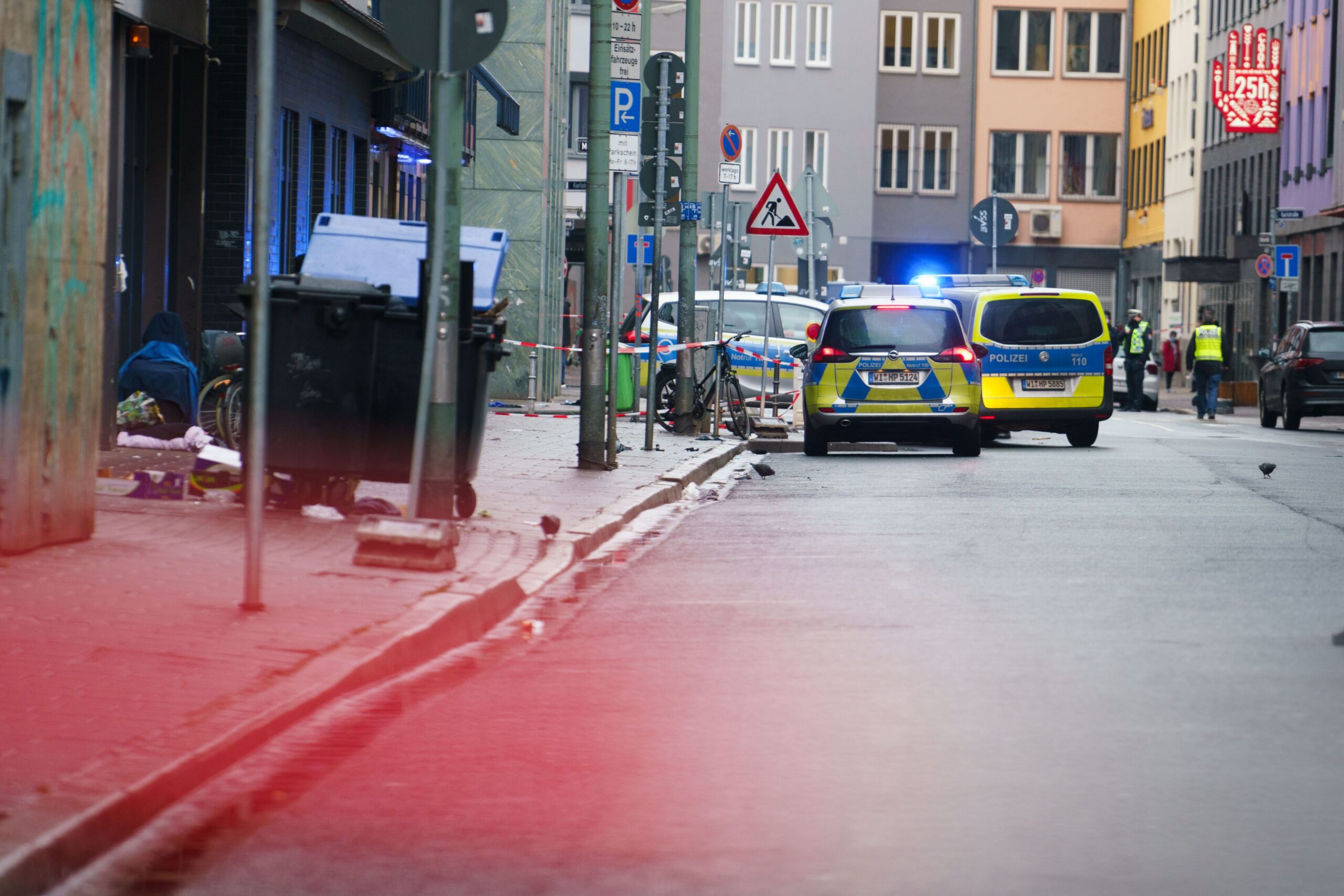 26 January 2021, Hessen, Frankfurt/Main: Police vehicles park in Frankfurt's Bahnhofsviertel in Niddastrasse, where there was a suspected knife attack with several people injured this morning. A suspect has been arrested, a police spokesman said. Photo: Frank Rumpenhorst/dpa