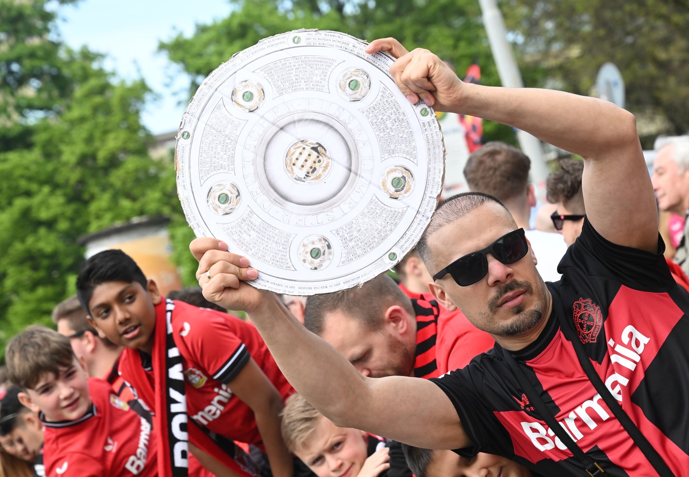 14 April 2024, North Rhine-Westphalia, Leverkusen: Soccer, Bundesliga, Bayer 04 Leverkusen - SV Werder Bremen, Matchday 29, BayArena. A Leverkusen fan holds a stylized championship trophy. The fans await the team bus and create a great atmosphere before the game.,Image: 864746459, License: Rights-managed, Restrictions: , Model Release: no