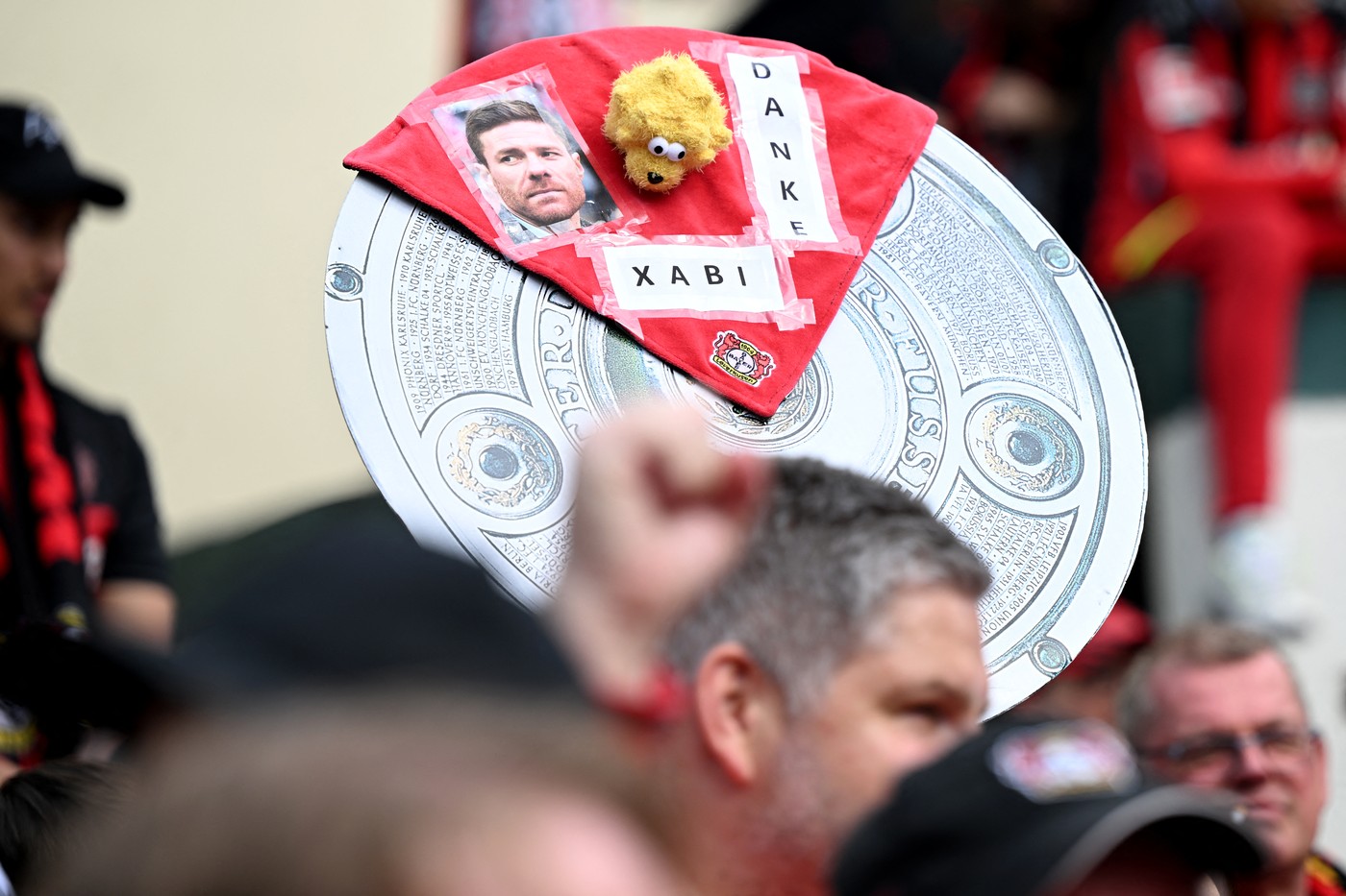 14 April 2024, North Rhine-Westphalia, Leverkusen: Soccer, Bundesliga, Bayer 04 Leverkusen - SV Werder Bremen, Matchday 29, BayArena. Leverkusen fans hold a stylized championship trophy with the inscription 