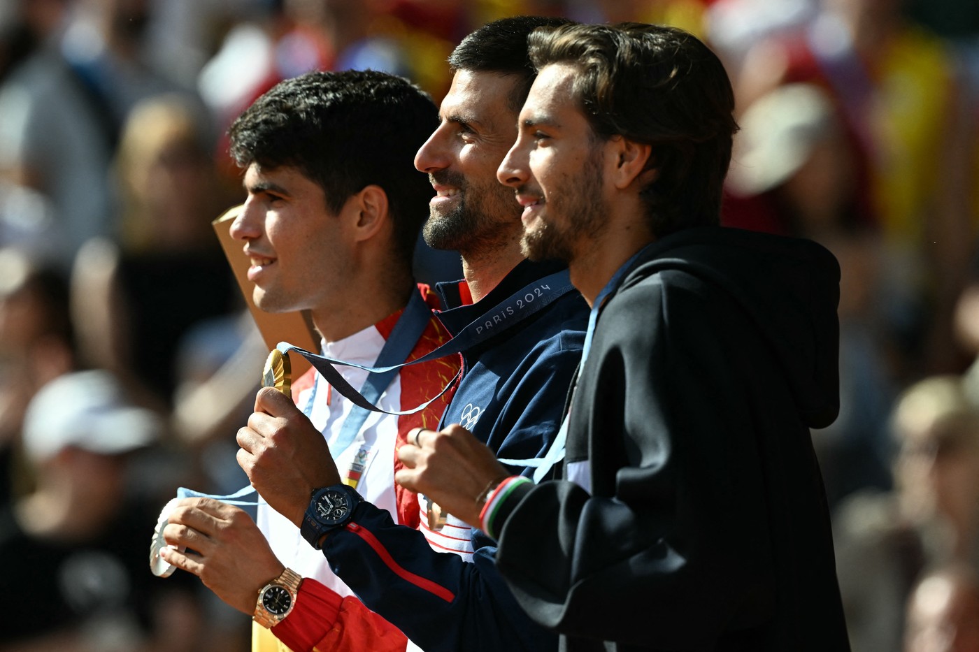 (L-R) Silver medallist Spain's Carlos Alcaraz, gold medallist, Serbia's Novak Djokovic and bronze medallist Italy's Lorenzo Musetti pose with their medals on the podium at the presentation ceremony for the men's singles tennis event on Court Philippe-Chatrier at the Roland-Garros Stadium during the Paris 2024 Olympic Games, in Paris on August 4, 2024.,Image: 895909330, License: Rights-managed, Restrictions: , Model Release: no
